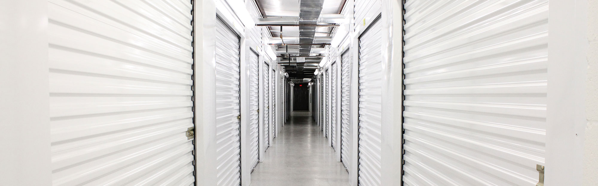 Hallway lined with white roll-up storage unit doors